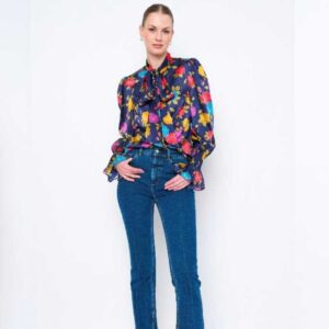 A woman wearing a vibrant blouse and jeans